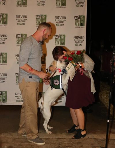 Veteran and service dog giving roses to trainer at Got Your Six Support Dogs graduation ceremony
