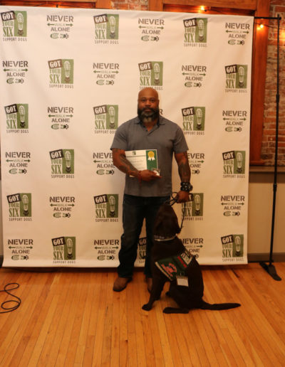 Veteran with certificate and black lab service dog at Got Your Six Support Dogs graduation ceremony